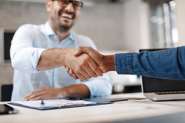 two men shaking hands over a desk